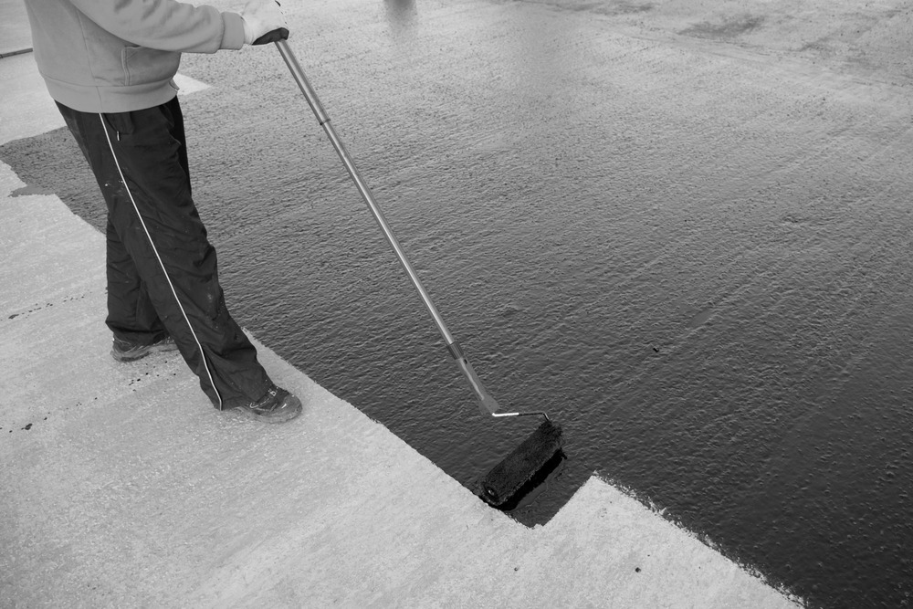 hombre pasando rodillo con pintura impermeabilizante en suelo